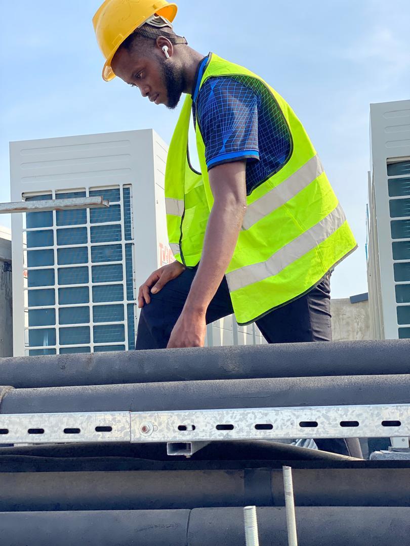 Technician in high-visibility gear on a rooftop plant area